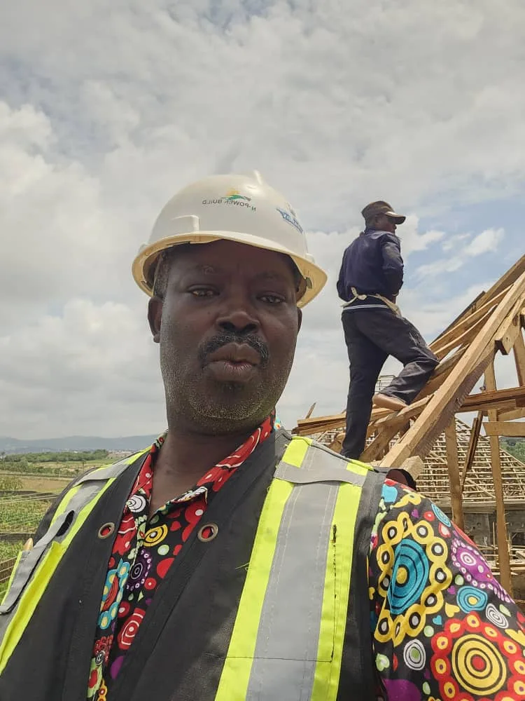 Person wearing a hard hat and safety vest at a construction site